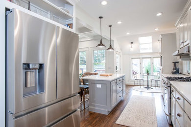 Example of a huge u-shaped dark wood floor and brown floor eat-in kitchen design in Atlanta with a farmhouse sink, raised-panel cabinets, gray cabinets, gray backsplash, stainless steel appliances, an island and white countertops
