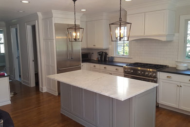 Eat-in kitchen - large transitional u-shaped light wood floor and brown floor eat-in kitchen idea in New York with an undermount sink, shaker cabinets, white cabinets, marble countertops, white backsplash, subway tile backsplash, stainless steel appliances and an island
