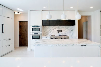 Example of a large minimalist u-shaped ceramic tile and white floor eat-in kitchen design in Orange County with an undermount sink, flat-panel cabinets, white cabinets, granite countertops, multicolored backsplash, marble backsplash, stainless steel appliances, an island and multicolored countertops