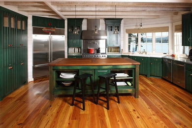 Design ideas for a large rustic l-shaped open plan kitchen in Other with a built-in sink, green cabinets, white splashback, stainless steel appliances, medium hardwood flooring, an island and stainless steel worktops.