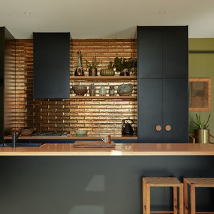 Contemporary galley kitchen in Melbourne with a drop-in sink, flat-panel cabinets, black cabinets, metallic splashback, medium hardwood floors, with island, brown floor and beige benchtop.
