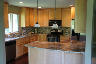 Mid-sized elegant brown floor and laminate floor enclosed kitchen photo in Minneapolis with a double-bowl sink, recessed-panel cabinets, light wood cabinets, granite countertops, brown backsplash, glass tile backsplash, stainless steel appliances and a peninsula