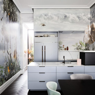 This is an example of an eclectic galley kitchen in Melbourne with an undermount sink, flat-panel cabinets, grey cabinets, panelled appliances, dark hardwood floors, a peninsula, black floor and white benchtop.