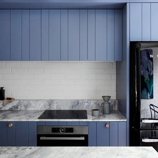 Design ideas for a small contemporary galley open plan kitchen in Melbourne with an undermount sink, blue cabinets, quartzite benchtops, white splashback, brick splashback, black appliances, medium hardwood floors, with island, grey floor, flat-panel cabinets and grey benchtop.