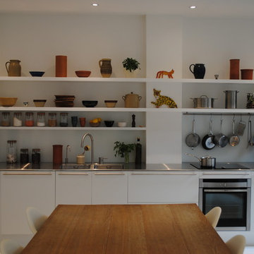 Flat fronted matt white kitchen with long open shelves.