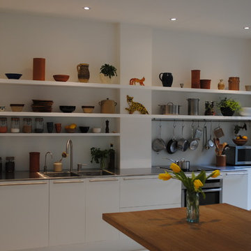 Flat fronted matt white kitchen with long open shelves.