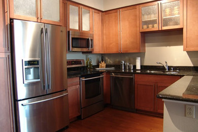 Example of a small trendy u-shaped dark wood floor enclosed kitchen design in Jacksonville with an undermount sink, shaker cabinets, medium tone wood cabinets, granite countertops, stainless steel appliances and a peninsula