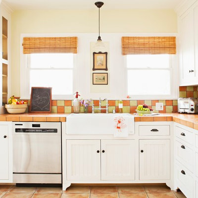 Example of a mid-sized cottage chic l-shaped terra-cotta tile eat-in kitchen design in Los Angeles with beaded inset cabinets, white cabinets, a farmhouse sink, tile countertops, terra-cotta backsplash, stainless steel appliances and multicolored backsplash