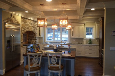 Eat-in kitchen - large traditional l-shaped medium tone wood floor eat-in kitchen idea in Philadelphia with a farmhouse sink, shaker cabinets, white cabinets, solid surface countertops, stainless steel appliances and two islands