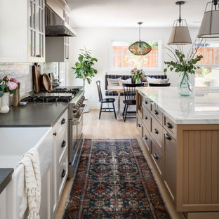 Design ideas for a large beach style l-shaped eat-in kitchen in San Diego with a farmhouse sink, shaker cabinets, light wood cabinets, solid surface benchtops, porcelain splashback, vinyl floors, with island and grey benchtop.