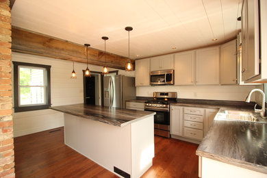 Example of a mid-sized country l-shaped medium tone wood floor and brown floor eat-in kitchen design in New York with a single-bowl sink, shaker cabinets, gray cabinets, laminate countertops, white backsplash, wood backsplash, stainless steel appliances and an island