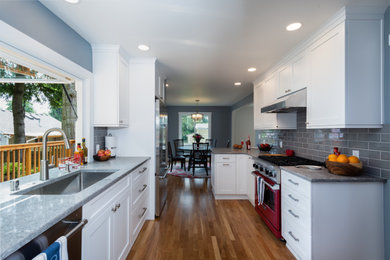 Photo of a small galley kitchen/diner in Seattle with a submerged sink, shaker cabinets, white cabinets, engineered stone countertops, grey splashback, porcelain splashback, coloured appliances, medium hardwood flooring, a breakfast bar, blue floors and grey worktops.