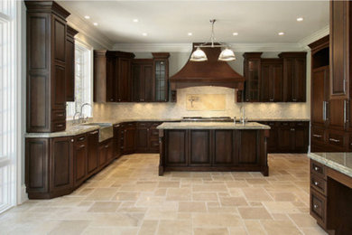 Large elegant travertine floor kitchen photo in Other with raised-panel cabinets, dark wood cabinets, granite countertops and an island