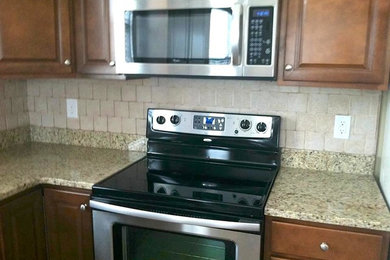 Example of a mid-sized classic kitchen design in Indianapolis with a double-bowl sink, raised-panel cabinets, dark wood cabinets, granite countertops, ceramic backsplash and stainless steel appliances