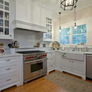 Traditional kitchen designs - Example of a classic kitchen design in Tampa with glass-front cabinets, stainless steel appliances and a farmhouse sink