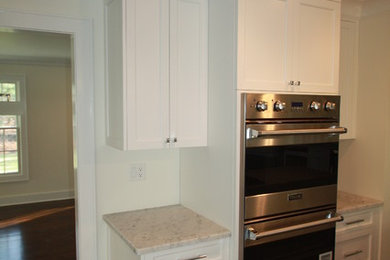 Example of a mid-sized classic dark wood floor kitchen design in New York with an undermount sink, white cabinets, marble countertops, stainless steel appliances and two islands