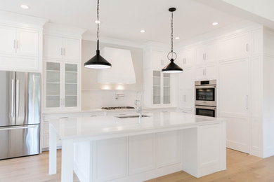 Inspiration for a large transitional l-shaped light wood floor and beige floor kitchen remodel in Other with an undermount sink, beaded inset cabinets, white cabinets, quartz countertops, white backsplash, quartz backsplash, stainless steel appliances, an island and white countertops