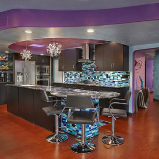 This is an example of a large eclectic l-shaped kitchen in Phoenix with an undermount sink, flat-panel cabinets, granite benchtops, glass tile splashback, stainless steel appliances, medium hardwood floors, with island, brown floor, black cabinets, multi-coloured splashback and grey benchtop.
