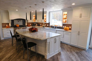 Example of a large transitional l-shaped dark wood floor and brown floor enclosed kitchen design in New York with an undermount sink, raised-panel cabinets, white cabinets, quartzite countertops, gray backsplash, porcelain backsplash, stainless steel appliances, an island and white countertops