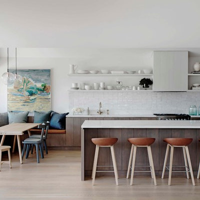 Example of a beach style galley light wood floor eat-in kitchen design in Sydney with white backsplash and a peninsula