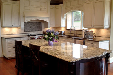 Example of a large classic l-shaped medium tone wood floor and brown floor eat-in kitchen design in Detroit with white cabinets, beige backsplash, stainless steel appliances, an island, an undermount sink, recessed-panel cabinets and granite countertops
