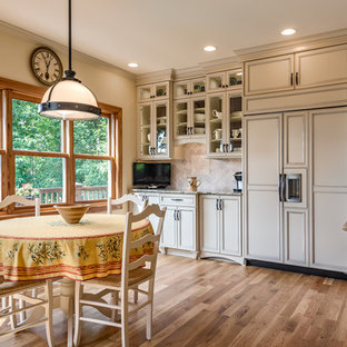 Design ideas for a large traditional galley eat-in kitchen in Charlotte with an undermount sink, glass-front cabinets, beige cabinets, granite benchtops, beige splashback, stone tile splashback, panelled appliances, medium hardwood floors and with island.