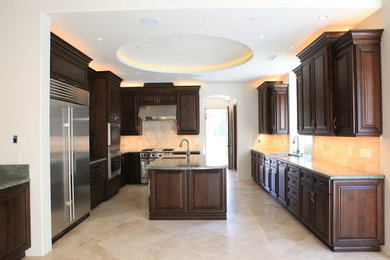 Example of a classic u-shaped limestone floor kitchen design in Los Angeles with an island, raised-panel cabinets, brown cabinets, granite countertops and stainless steel appliances