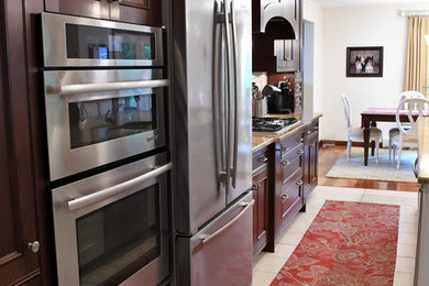 Eat-in kitchen - large mediterranean single-wall ceramic tile and beige floor eat-in kitchen idea in Other with a double-bowl sink, recessed-panel cabinets, dark wood cabinets, granite countertops, beige backsplash, porcelain backsplash, stainless steel appliances and an island
