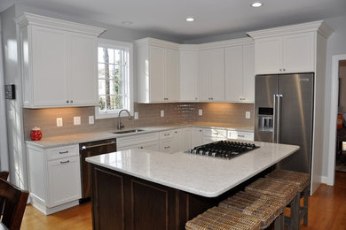 Example of a mid-sized minimalist u-shaped eat-in kitchen design in DC Metro with an undermount sink, white cabinets, stainless steel appliances and an island