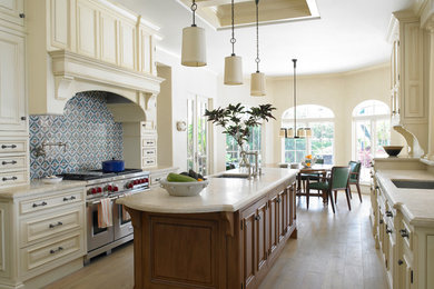 Inspiration for a large mediterranean galley light wood floor and beige floor eat-in kitchen remodel in Miami with an undermount sink, raised-panel cabinets, beige cabinets, multicolored backsplash, stainless steel appliances, an island, granite countertops and mosaic tile backsplash
