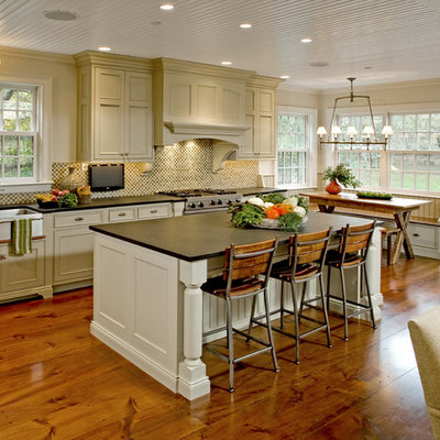 Eat-in kitchen - large traditional l-shaped medium tone wood floor eat-in kitchen idea in Philadelphia with a farmhouse sink, recessed-panel cabinets, beige cabinets, soapstone countertops, multicolored backsplash, mosaic tile backsplash, stainless steel appliances and an island