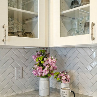 This is an example of a mid-sized shabby-chic style l-shaped separate kitchen in Dallas with an undermount sink, white cabinets, marble benchtops, white splashback, porcelain splashback, stainless steel appliances, with island, shaker cabinets, porcelain floors and beige floor.