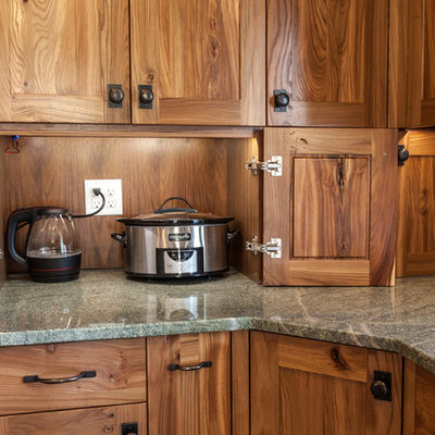 Inspiration for a mid-sized craftsman l-shaped porcelain tile eat-in kitchen remodel in Denver with a farmhouse sink, recessed-panel cabinets, medium tone wood cabinets, granite countertops, green backsplash, glass tile backsplash, paneled appliances and an island