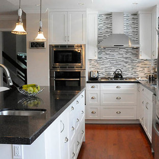 Design ideas for a mid-sized contemporary u-shaped eat-in kitchen in Vancouver with an undermount sink, shaker cabinets, grey splashback, stainless steel appliances, medium hardwood floors, with island, white cabinets, terrazzo benchtops and brown floor.