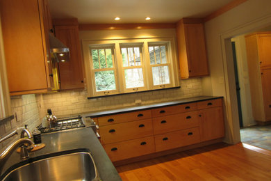 他の地域にあるトラディショナルスタイルのおしゃれなキッチン (ダブルシンク、シェーカースタイル扉のキャビネット、中間色木目調キャビネット、ソープストーンカウンター、白いキッチンパネル、サブウェイタイルのキッチンパネル、シルバーの調理設備、無垢フローリング、茶色い床、グレーのキッチンカウンター) の写真
