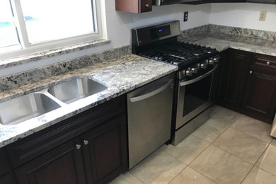 Kitchen - mid-sized traditional l-shaped kitchen idea in St Louis with an undermount sink, raised-panel cabinets, dark wood cabinets, granite countertops, stainless steel appliances and multicolored countertops