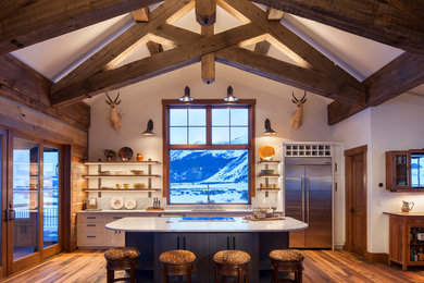 Photo of a rustic galley open plan kitchen in Denver with a submerged sink, shaker cabinets, white cabinets, stainless steel appliances, dark hardwood flooring, an island, brown floors and white worktops.