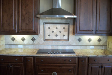 Elegant single-wall kitchen photo in Houston with raised-panel cabinets, dark wood cabinets, granite countertops, beige backsplash and stone tile backsplash
