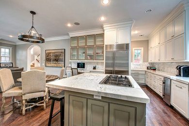 Eat-in kitchen - mid-sized transitional l-shaped medium tone wood floor eat-in kitchen idea in Houston with beaded inset cabinets, white cabinets, marble countertops, white backsplash, stone slab backsplash, stainless steel appliances and an island
