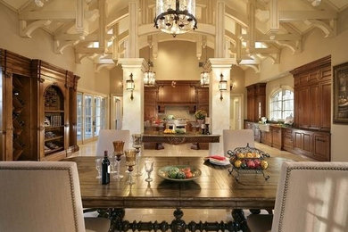 Eat-in kitchen - large traditional u-shaped limestone floor eat-in kitchen idea in New York with a farmhouse sink, raised-panel cabinets, medium tone wood cabinets, granite countertops, beige backsplash, stone tile backsplash, paneled appliances and two islands