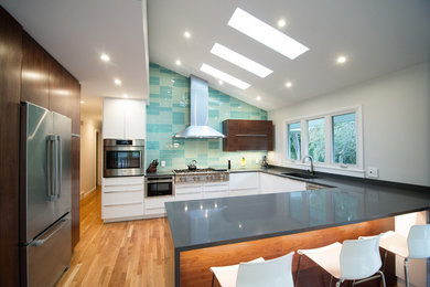 Medium sized contemporary u-shaped open plan kitchen in Detroit with a submerged sink, flat-panel cabinets, dark wood cabinets, engineered stone countertops, green splashback, glass tiled splashback, stainless steel appliances, light hardwood flooring, a breakfast bar, beige floors, grey worktops and a vaulted ceiling.