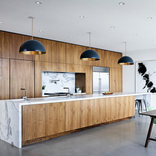 Diseño de cocina de galera, minimalista, abierta, con fregadero bajoencimera, armarios con paneles lisos, puertas de armario de madera oscura, encimera de mármol, salpicadero blanco, salpicadero de losas de piedra, electrodomésticos de acero inoxidable, suelo de cemento, una isla y suelo gris