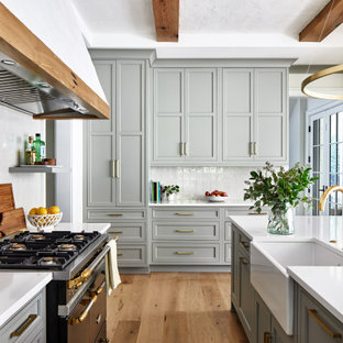 Idee per una grande cucina tradizionale con lavello stile country, ante in stile shaker, ante grigie, top in quarzo composito, paraspruzzi bianco, paraspruzzi con piastrelle in pietra, elettrodomestici neri, top bianco, pavimento in legno massello medio e pavimento marrone