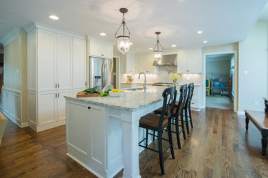 Open concept kitchen - transitional l-shaped medium tone wood floor open concept kitchen idea in Other with an undermount sink, shaker cabinets, white cabinets, granite countertops, gray backsplash, porcelain backsplash, stainless steel appliances and an island