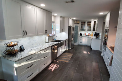 Example of a large minimalist u-shaped porcelain tile and gray floor kitchen design in Dallas with a farmhouse sink, shaker cabinets, white cabinets, quartzite countertops, gray backsplash, subway tile backsplash, stainless steel appliances, no island and multicolored countertops