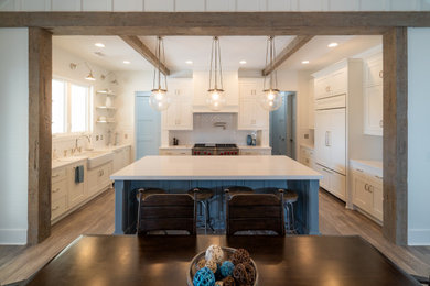 Inspiration for a mid-sized cottage galley brown floor eat-in kitchen remodel in Atlanta with a farmhouse sink, white cabinets, marble countertops and an island