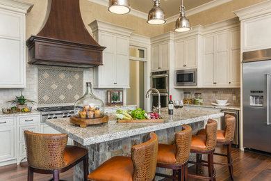 This is an example of a traditional kitchen in Atlanta with recessed-panel cabinets, beige cabinets, beige splashback, stainless steel appliances, dark hardwood flooring and an island.