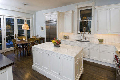 Eat-in kitchen - mid-sized traditional l-shaped dark wood floor and brown floor eat-in kitchen idea in Chicago with an undermount sink, shaker cabinets, white cabinets, marble countertops, white backsplash, ceramic backsplash, stainless steel appliances and an island