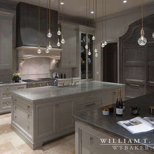 Photo of a large transitional l-shaped open plan kitchen in Atlanta with an integrated sink, recessed-panel cabinets, grey cabinets, marble benchtops, grey splashback, stone tile splashback, stainless steel appliances, travertine floors and multiple islands.