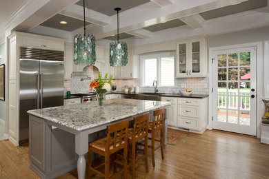 Eat-in kitchen - transitional l-shaped medium tone wood floor eat-in kitchen idea in DC Metro with a farmhouse sink, recessed-panel cabinets, white cabinets, granite countertops, white backsplash, stainless steel appliances, an island and subway tile backsplash
